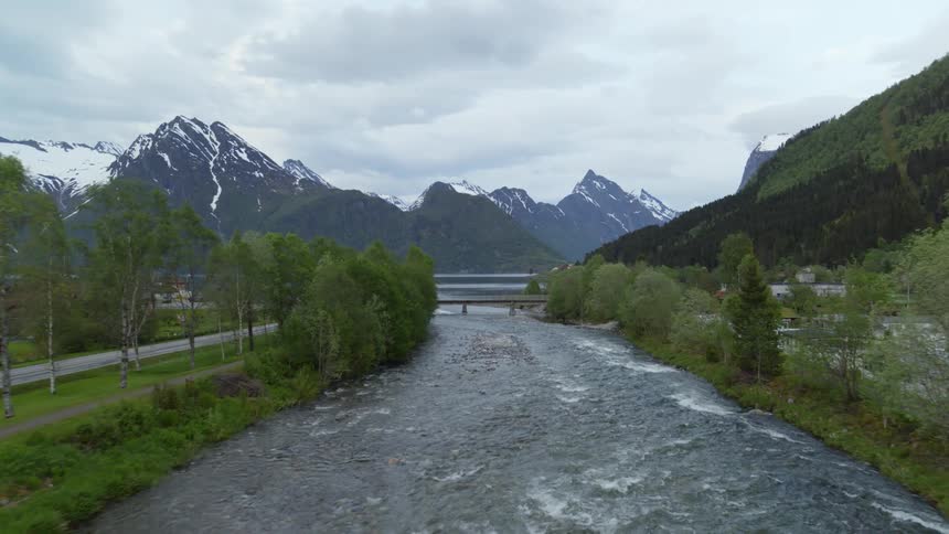 Glacial waters flowing into Norwegian fjords with mountains in background