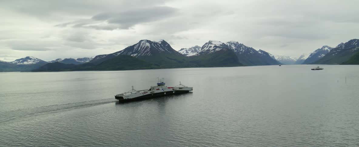 Aerial view of a ferry traveling on a lake near the mountains