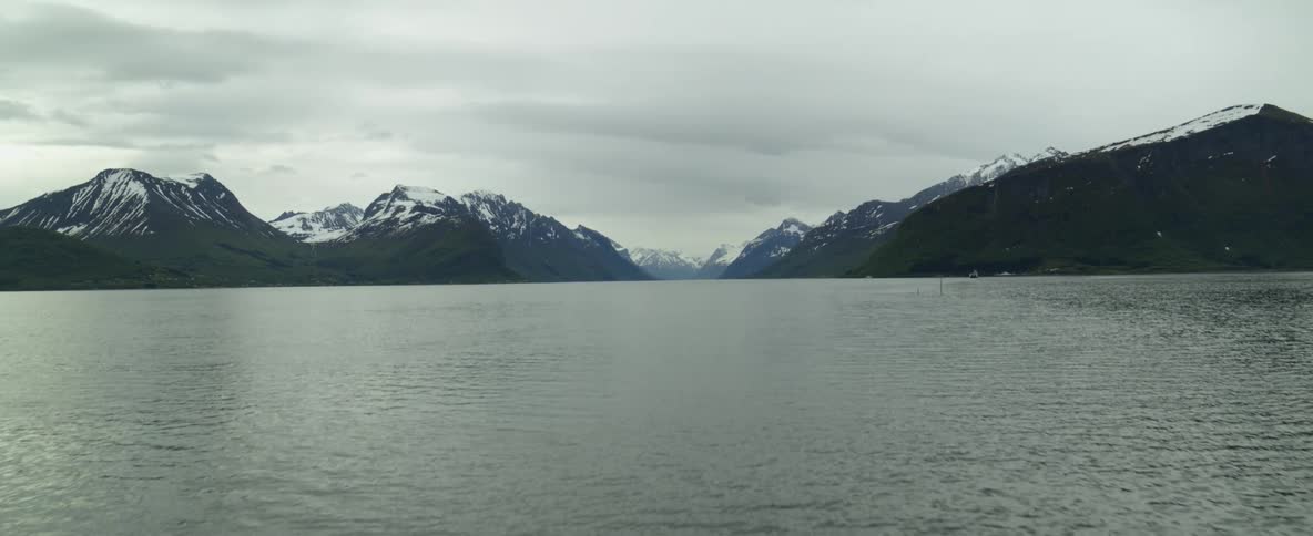 A rippled water surface leads to snow dusted mountain ridges and peaks