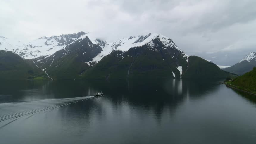 A ferry makes its way across the fjord with mountain and green hills