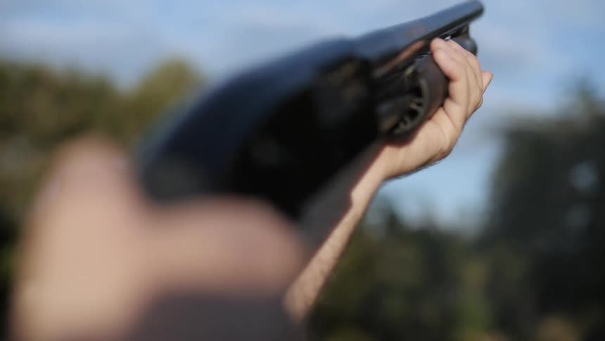 A person fires off a shotgun on a cloudy day