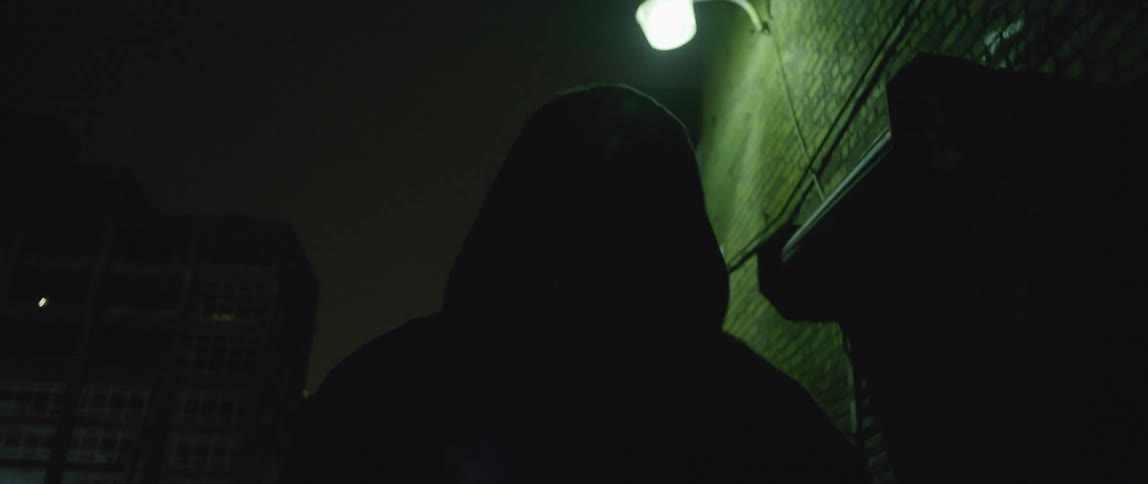 A person is walking down a dark alley at night