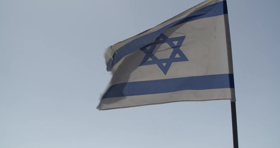 A white and blue flag blows in the wind of a clear sky