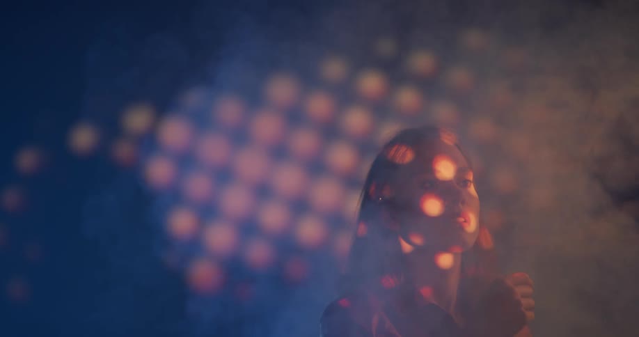 A teenager curiously holds her hands up in smoke in the air