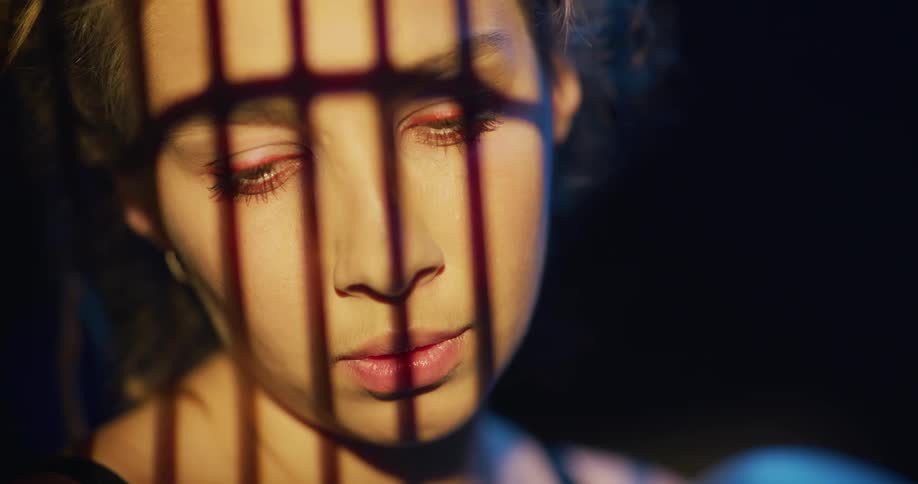 Close up of shadows on the face of a young woman sitting inside a dimly lit room
