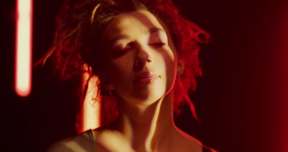 A woman is standing in a room and touching her face
