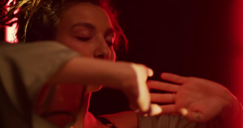 Close up of the face of a woman relaxing inside a dimly lit room under red lights