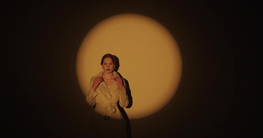 Relaxed woman modeling while reclined on a wall under a soft spotlight