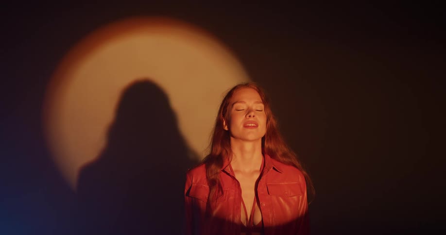A woman stands on stage in the spotlight and takes a deep breath