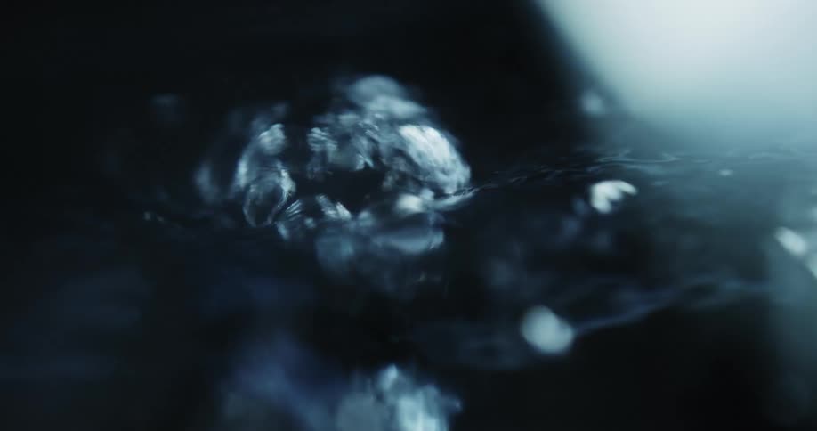 Close up of tiny air bubbles rising to the water surface on a dark environment
