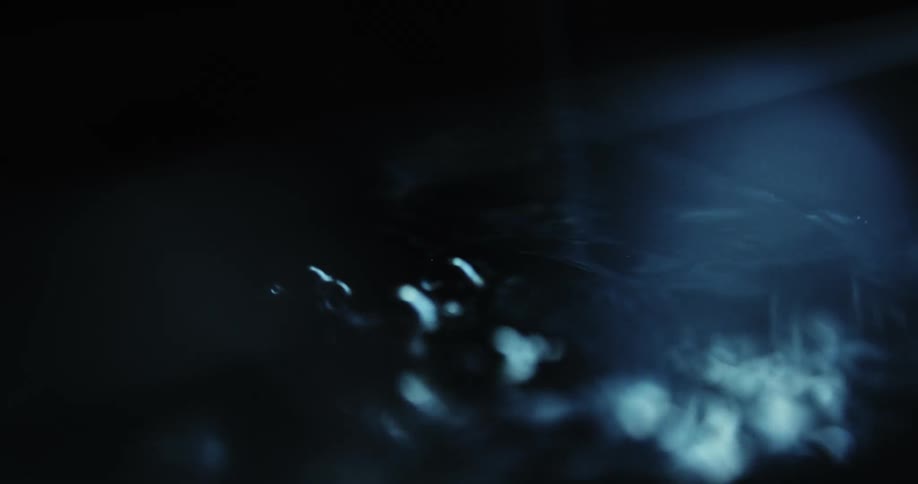 Light reflects off the surface of water as bubbles form and ripple out
