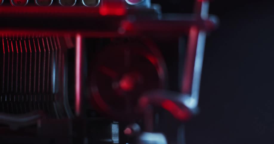 Close up of the rotating roll of tape on a working typewriter under red lights