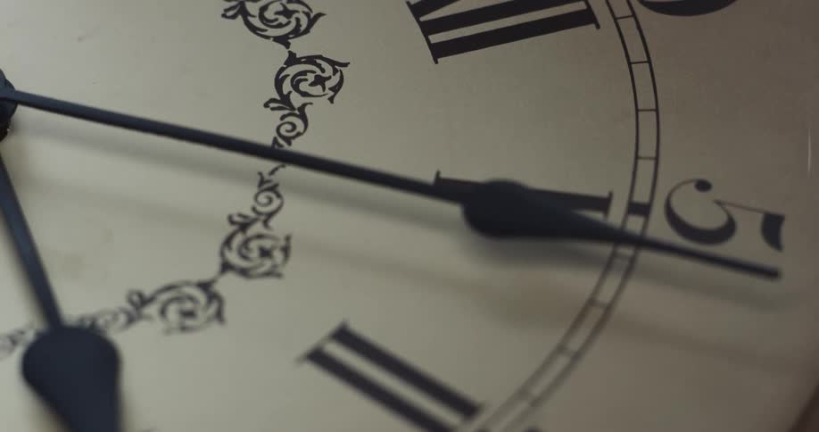 The hands of an analog clock cast a shadow on the clock face