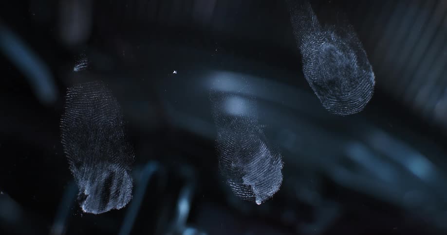 Flashing police lights are reflecting off a window that has fingerprints on it