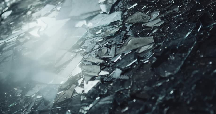 Light reflects on shards of shattered and broken glass on the ground