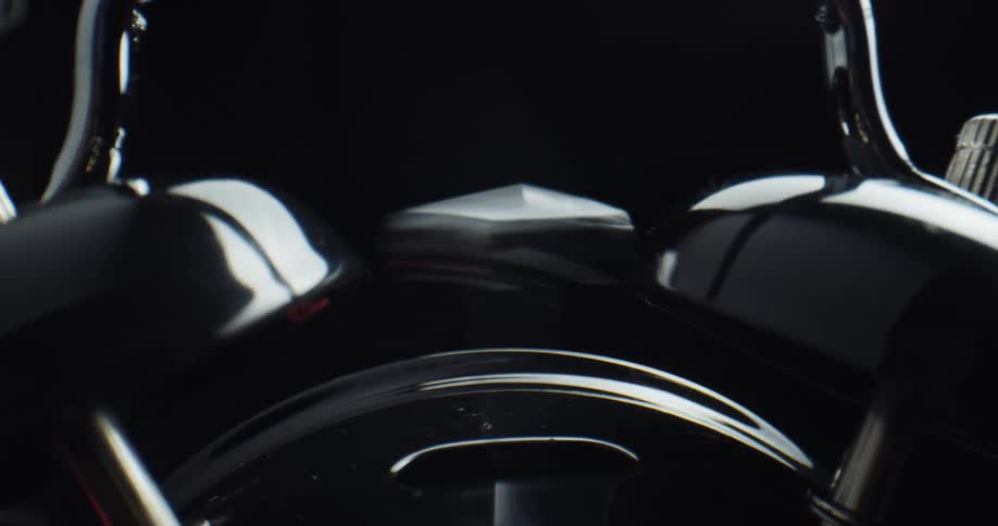 Close up of the hammer of an alarm clock ringing the bells inside a dark room