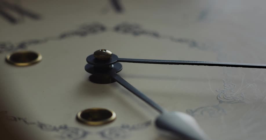 The hands of an analog clock cast a shadow on the clock face