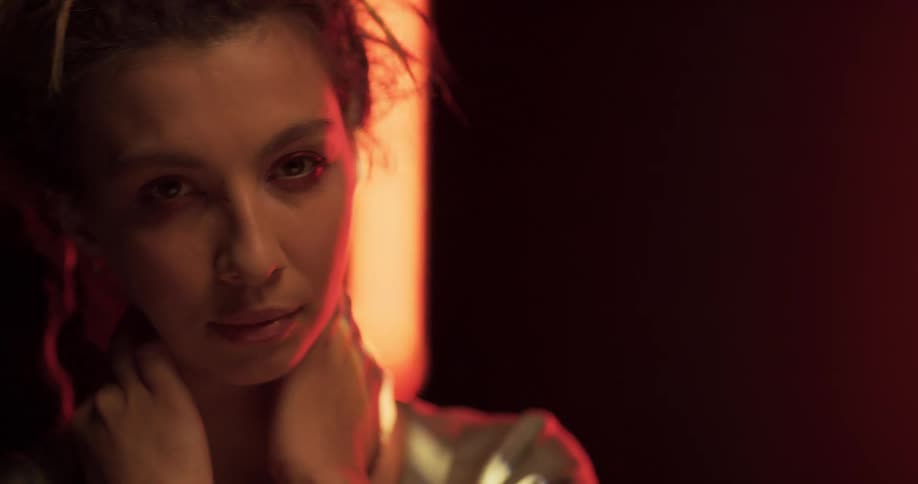 A woman is standing in a room with light shining on her face