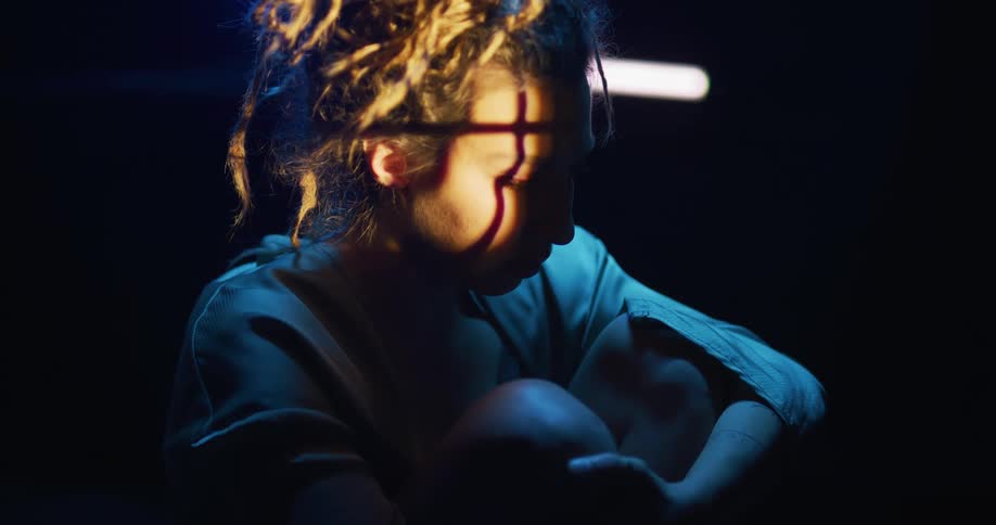 Close up of shadows on the face of a young woman sitting inside a dimly lit room