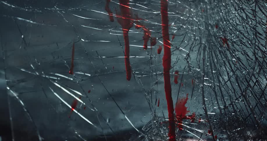 Blood stains over a broken glass reflecting flashing blue and red lights