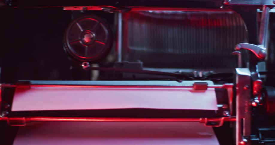 Red light is illuminating off of a vintage typewriter in the dark