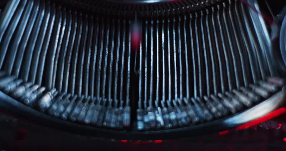 Light shines on the type bars of an old typewriter as they move