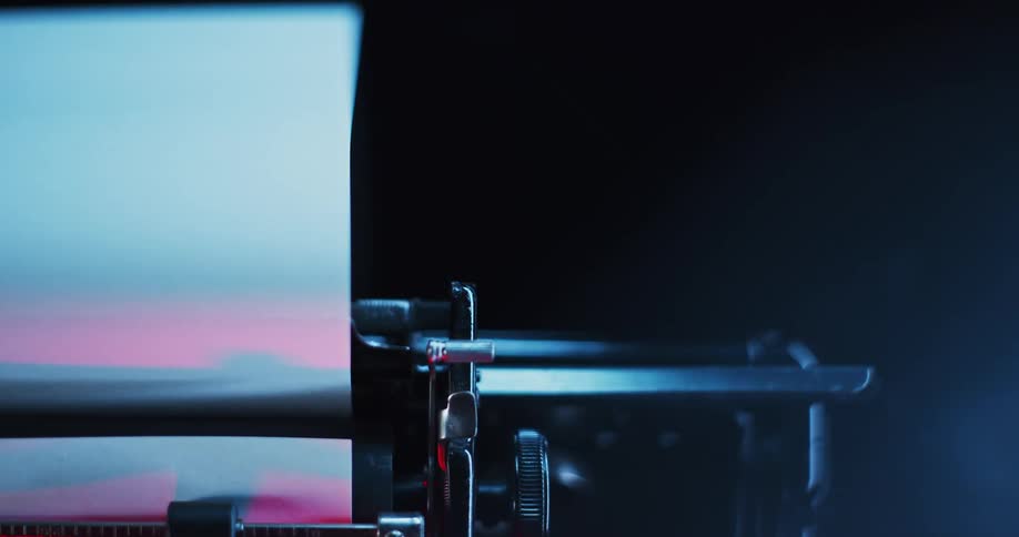 Paper rolled on a typewriter platen moving left to right under red and blue lights