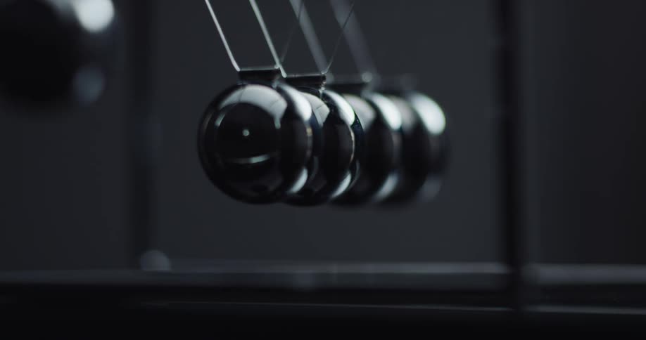 Metal balls are swinging back and forth hitting each other in a newtons cradle