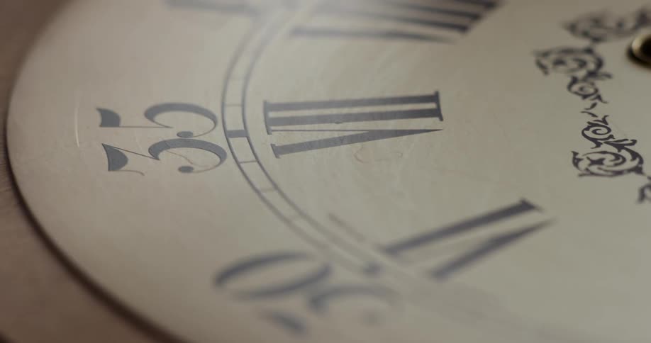 An analog clock is being filmed in slow motion as the camera turns around the clock