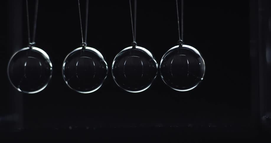 Glass spheres moving in a rhythmic motion and knocking one another