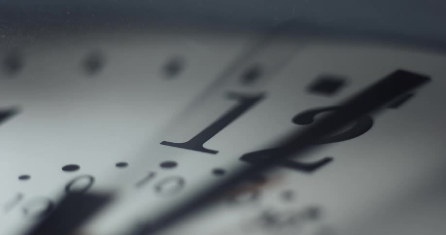 Extreme close up of the hands moving over the numbers on the face of an analog clock