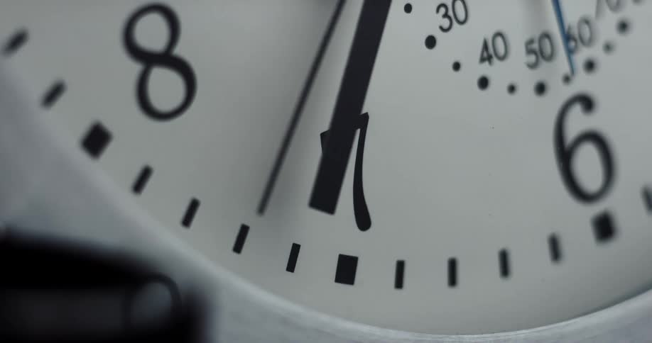 The hands of an analog clock cast a shadow on the clock face as they move
