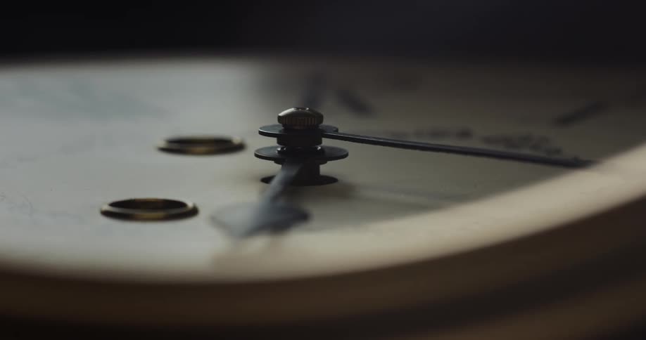 Arms and dial of an analog wall clock resting on the floor inside a dark room