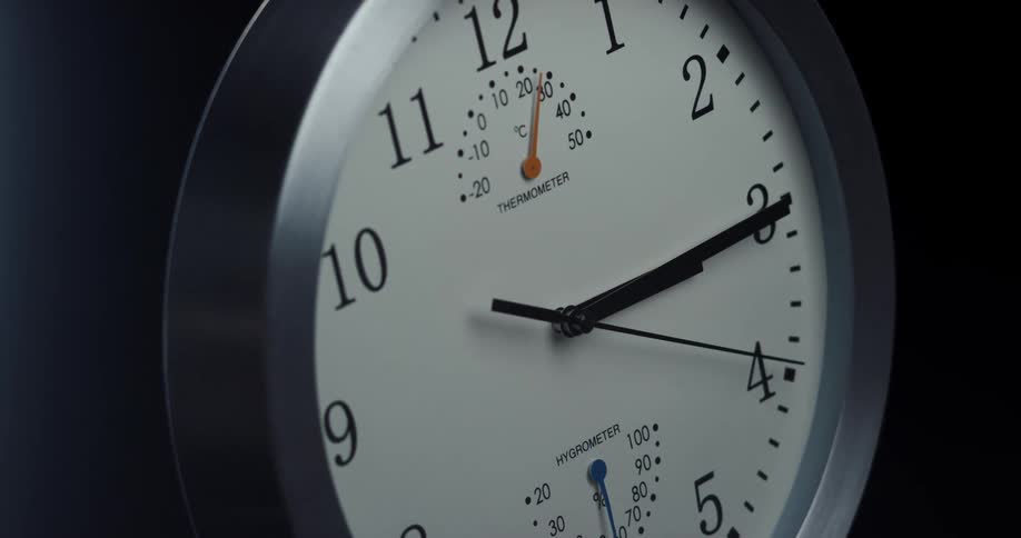 Close up of an analog clock slowly spinning against a black background