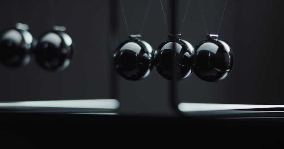 Metal balls are swinging back and forth hitting each other in a newtons cradle