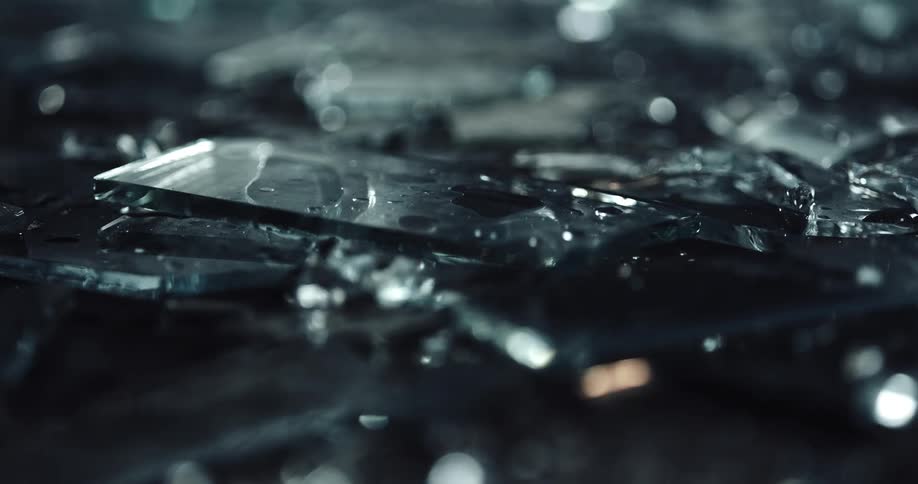 Close up of broken glass pieces with police lights displaying on