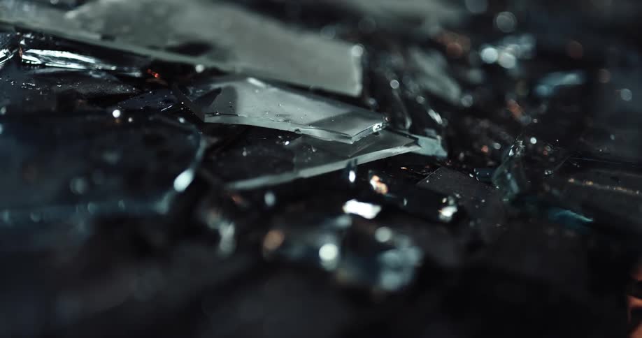 A pile of broken glass reflects blinking lights