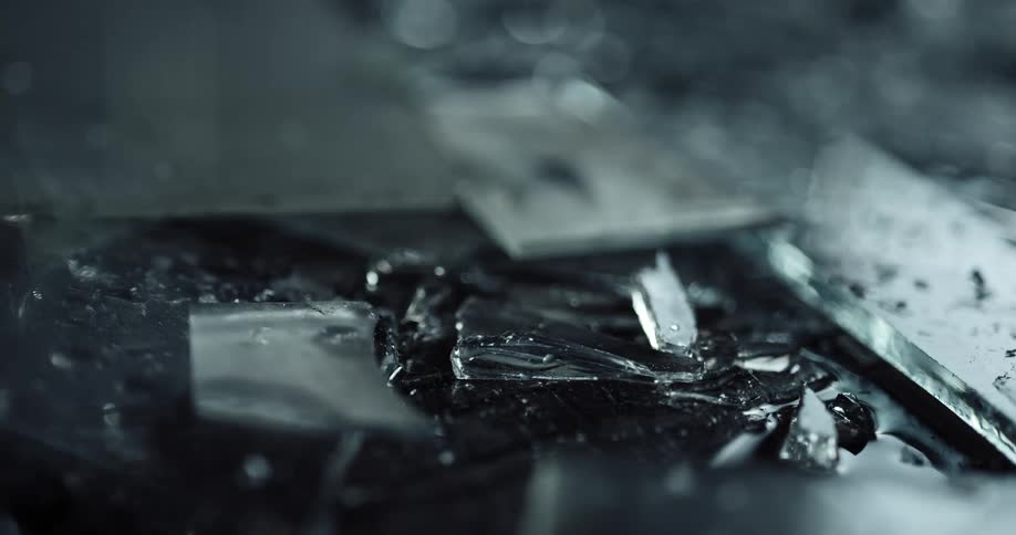 Close up of fragments of broken glass with police lights displaying on