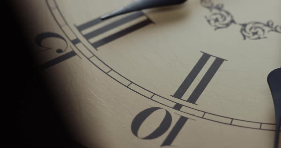 The hands of an analog clock cast a shadow on the clock face