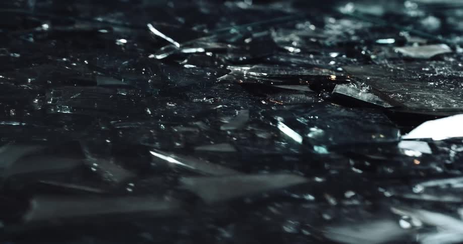 Close up of broken shards of glass on the ground at night