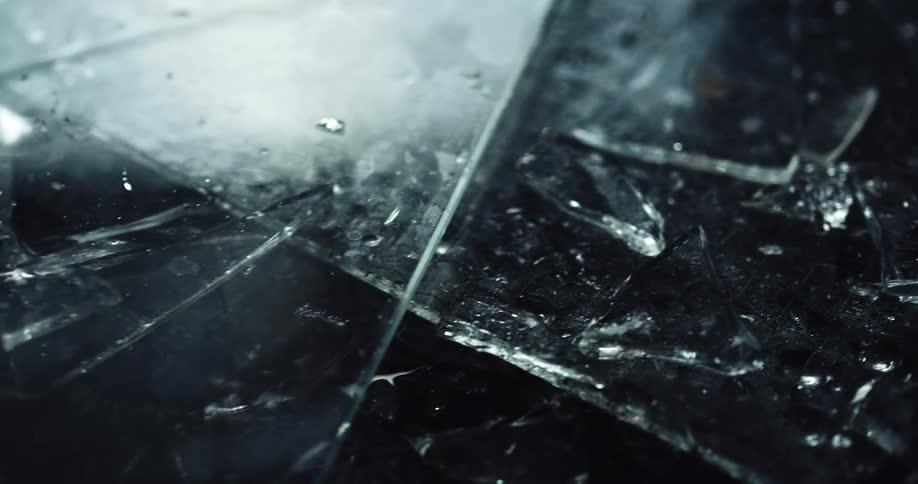 Close up of broken shards of glass on the ground at night
