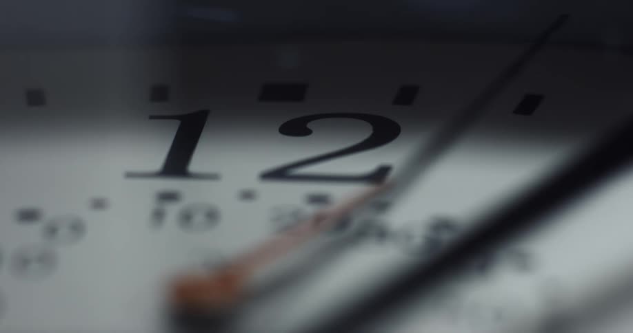 The hands of an analog clock cast a shadow on the clock face as they move