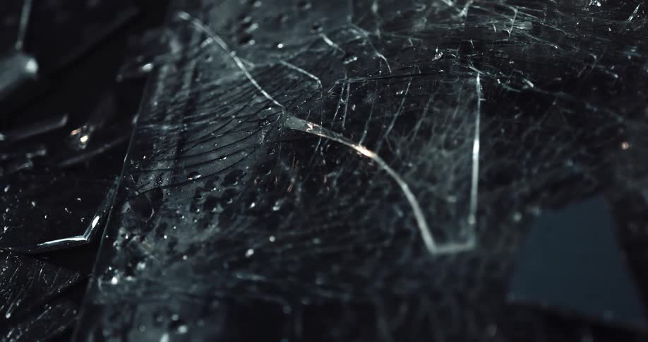 Pieces of broken glass sprinkled with water on the ground of a dark room