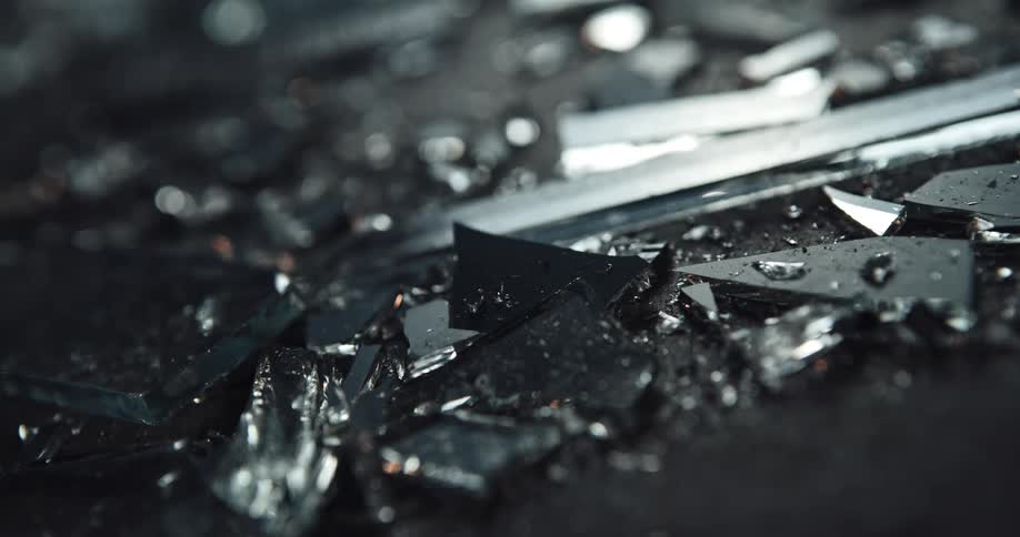 Close up of broken shards of glass on the ground at night