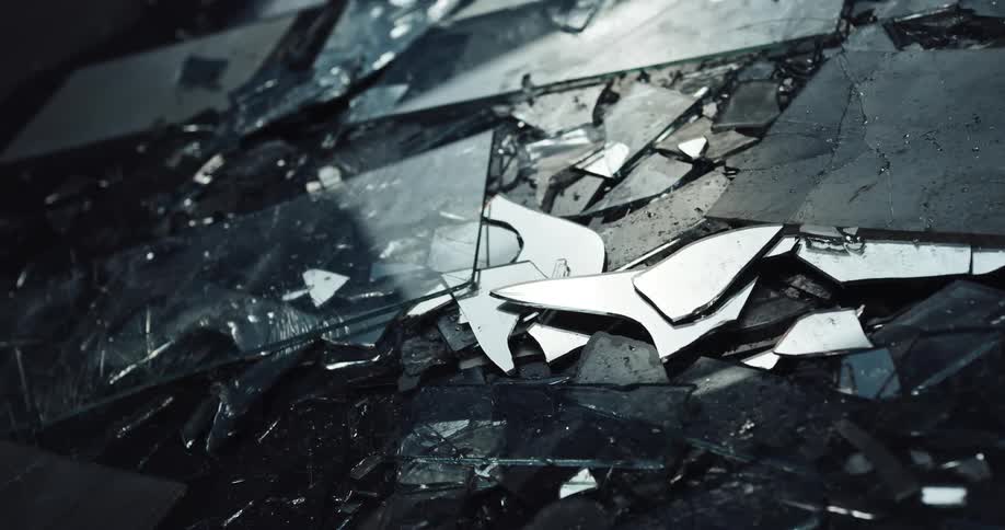 Light reflects on shards of broken glass that are on the ground