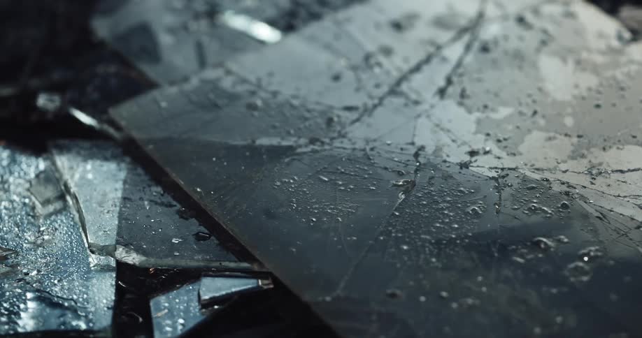 Flashing police lights are reflecting off of bloody and broken glass