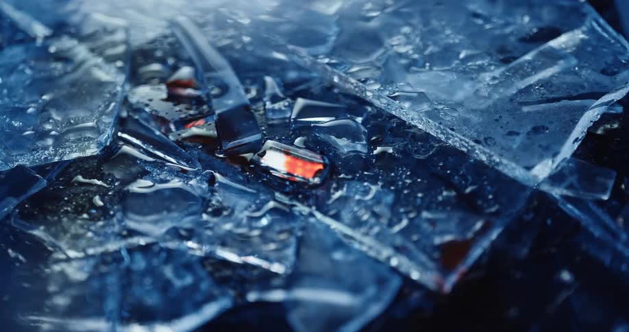 Pieces of broken glass sprinkled with water on the ground of a dark room reflecting light