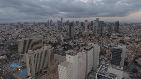 A large city with traffic moving and clouds hovering overhead
