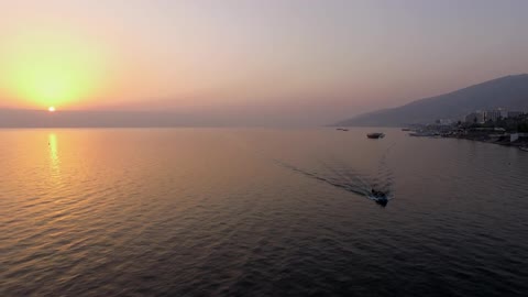 A boat floats on the ocean at sunset