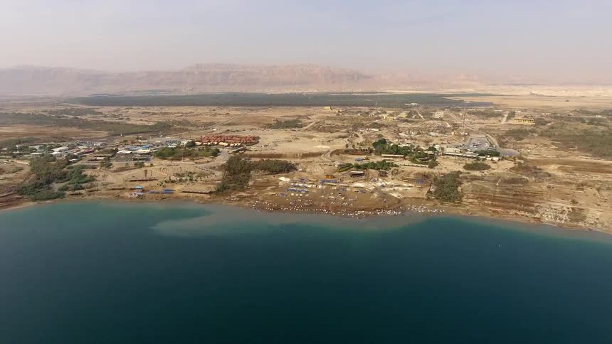 A coastline has hills leading to buildings